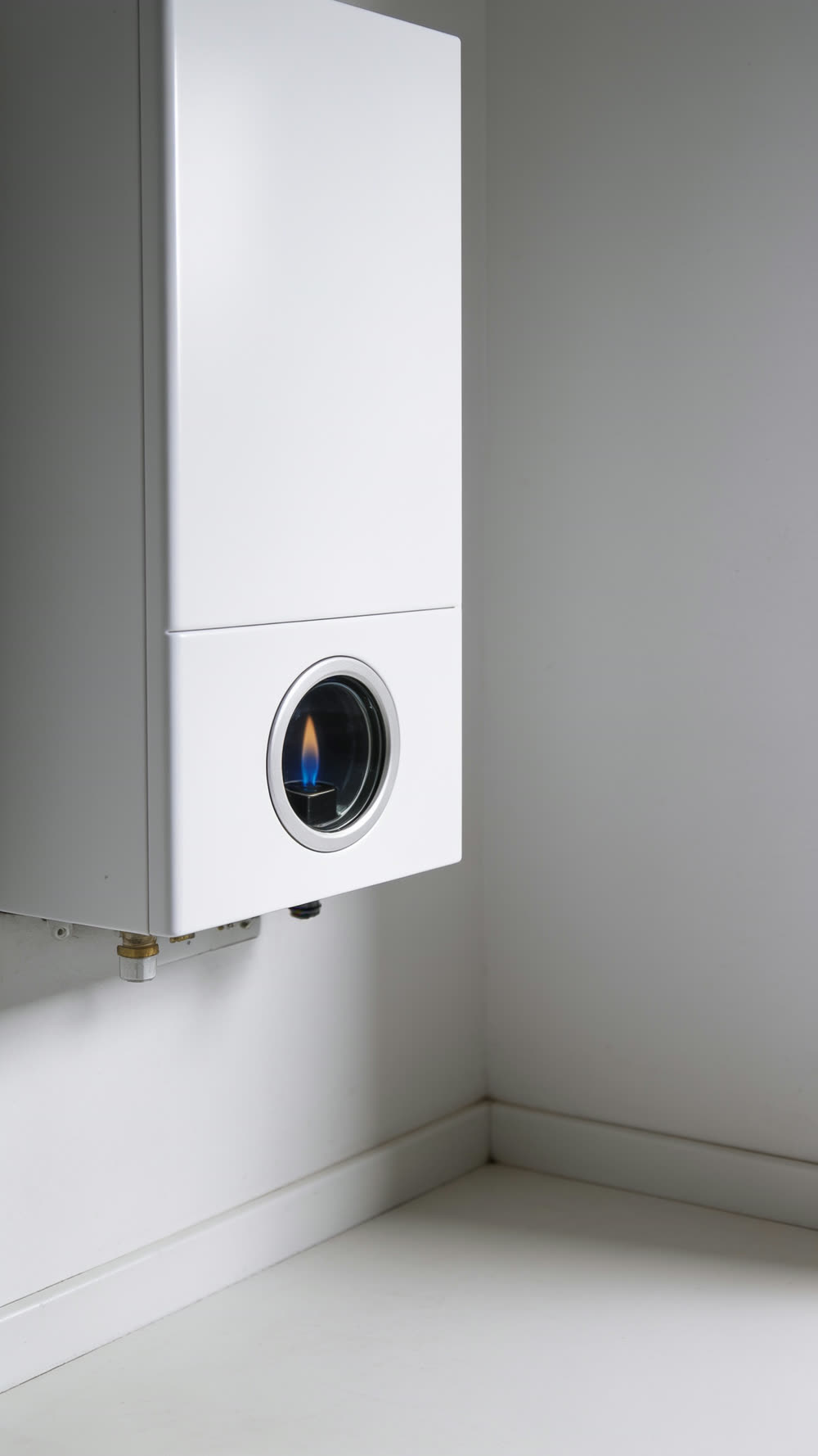 Extreme close view of a tiny, steady blue pilot flame seen through the small round glass inspection window of a plain white wall-mounted boiler.